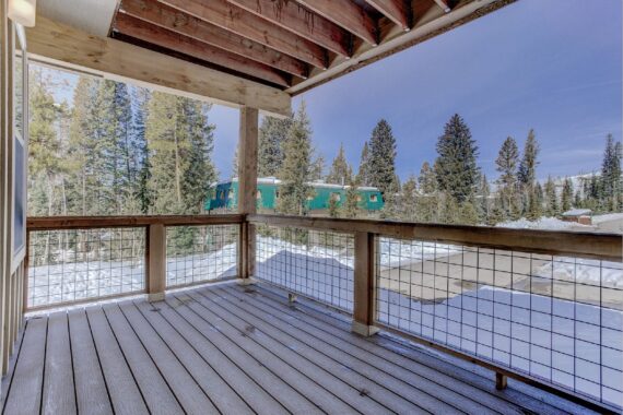 Snow-covered deck with wooded background and green building