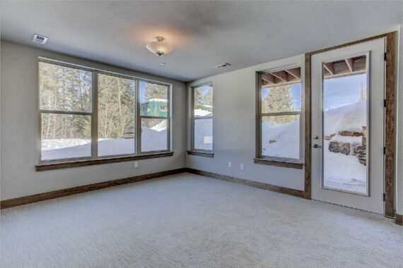 Empty room with large windows showing snowy landscape.