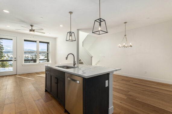 Modern kitchen with island, light fixtures, and wood floors.