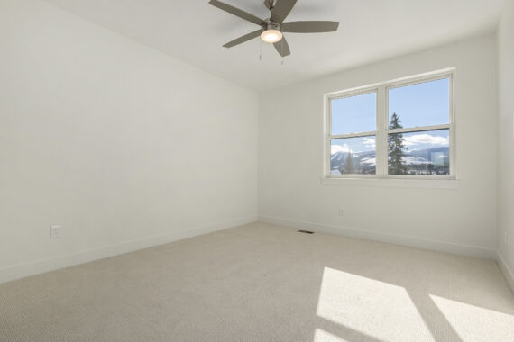 Empty room with beige carpet, ceiling fan, and large window with a mountain view