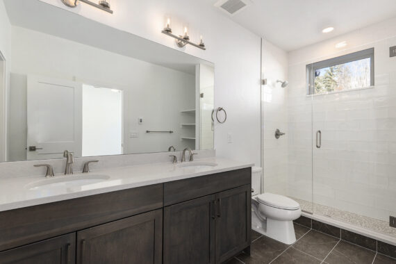 Modern bathroom with double sinks and glass shower.