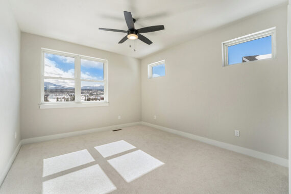 Empty room with three windows and a ceiling fan