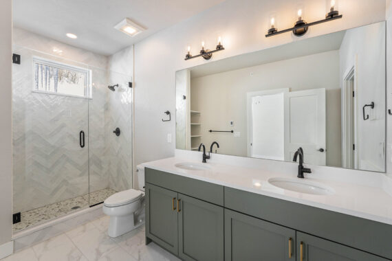 Modern bathroom with glass shower, vanity, and double sinks