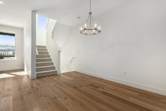 Modern interior with wooden floor, staircase, and chandelier