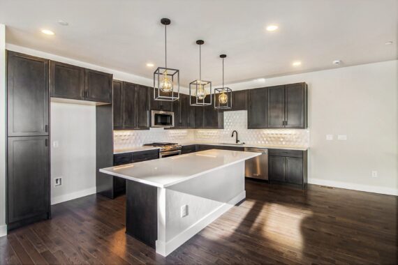 Modern kitchen with dark cabinets and island, pendant lights