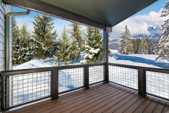 Snowy deck overlooking forested mountain landscape