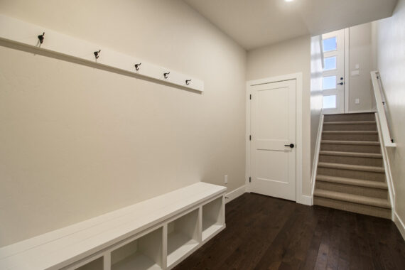 Entryway with white bench, hooks, and stairs.