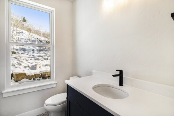 Bathroom with a black faucet and snowy window view