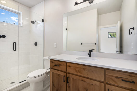 Modern bathroom with glass shower, toilet, and wooden vanity