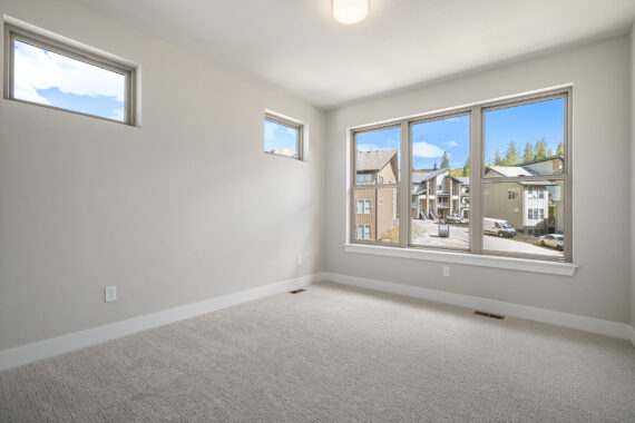 Empty room with beige carpet and large windows.