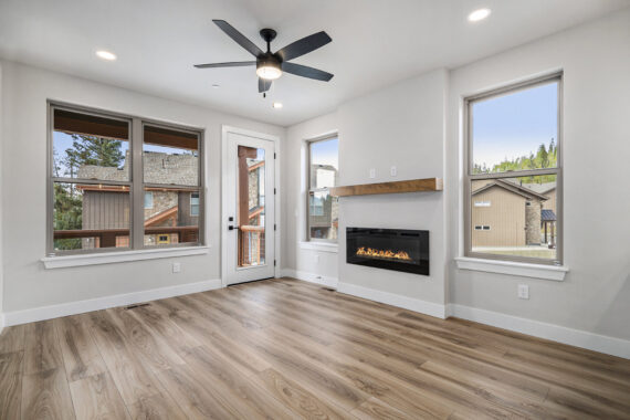 Living room with modern fireplace, large windows, and ceiling fan