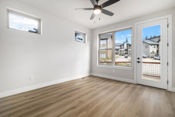 Empty room with wooden floor, ceiling fan, and large windows