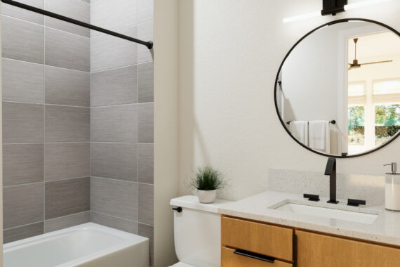 Modern bathroom with round mirror and gray tiles