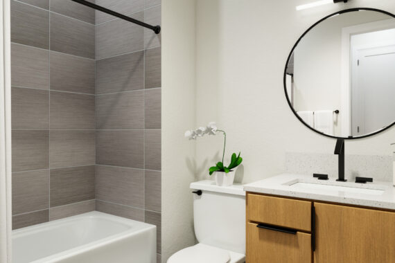 Modern bathroom with circular mirror and wooden cabinets