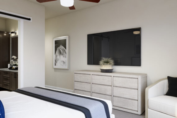 Modern bedroom with bed, dresser, TV, chair, and bathroom.