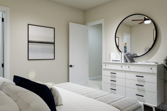 Bedroom with white dresser, round mirror, open closet