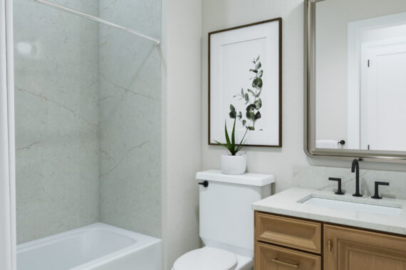 Modern bathroom with a tub, framed plant artwork, and mirror